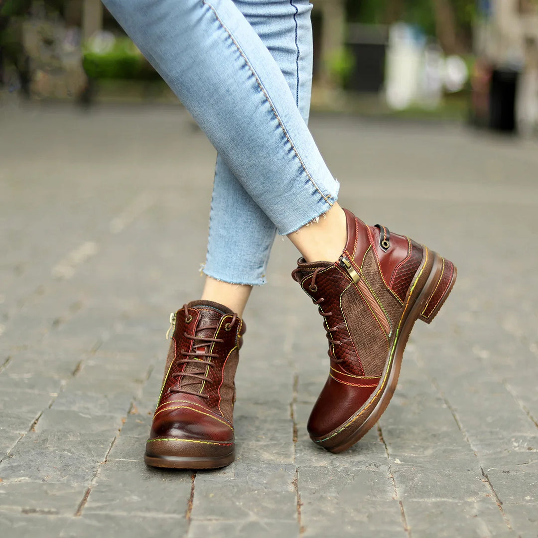 Woman wearing brown mixed leather ankle boots with contrast stitching, side view walking