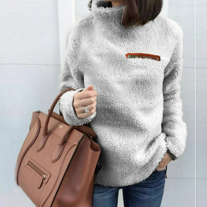 Woman wearing light grey sherpa turtleneck pullover with zip chest pocket