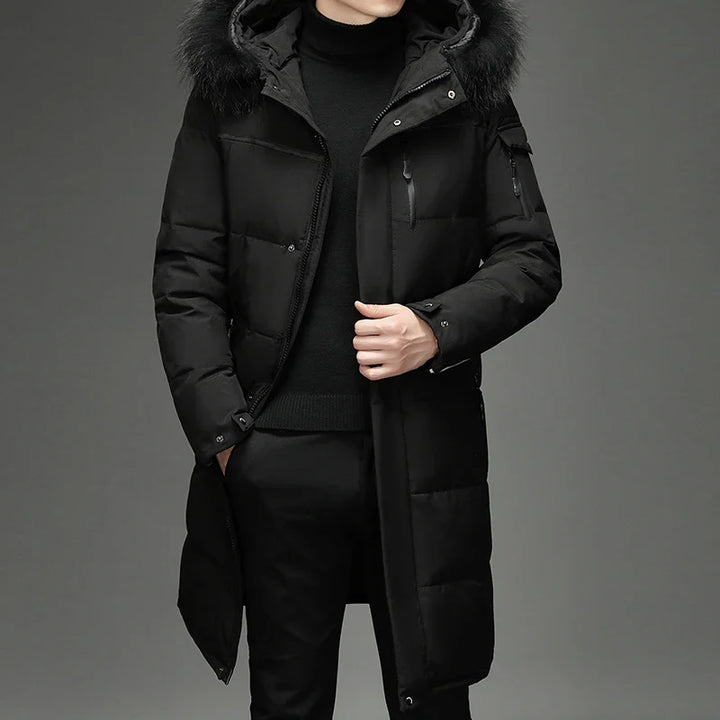 Man wearing black hooded down coat with fur trim, front view with hand in pocket