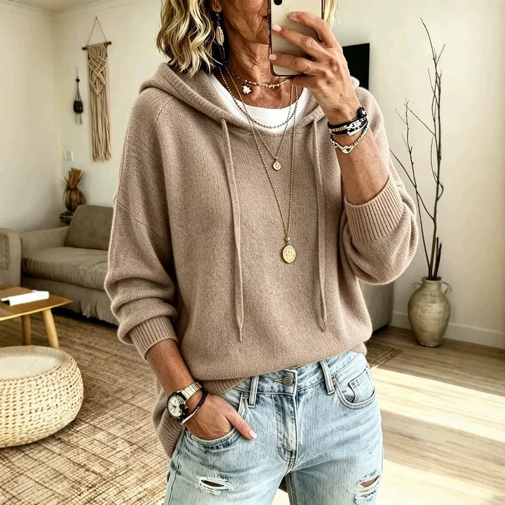 Woman wearing khaki knit drawstring hoodie with jeans, front view