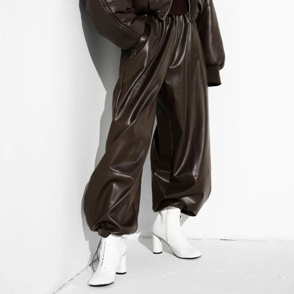 Woman wearing dark brown faux leather lantern pants with puffer jacket and white boots