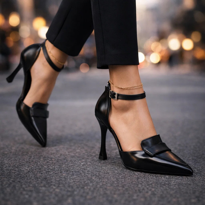 Black pointed-toe pumps with ankle strap worn walking outdoors