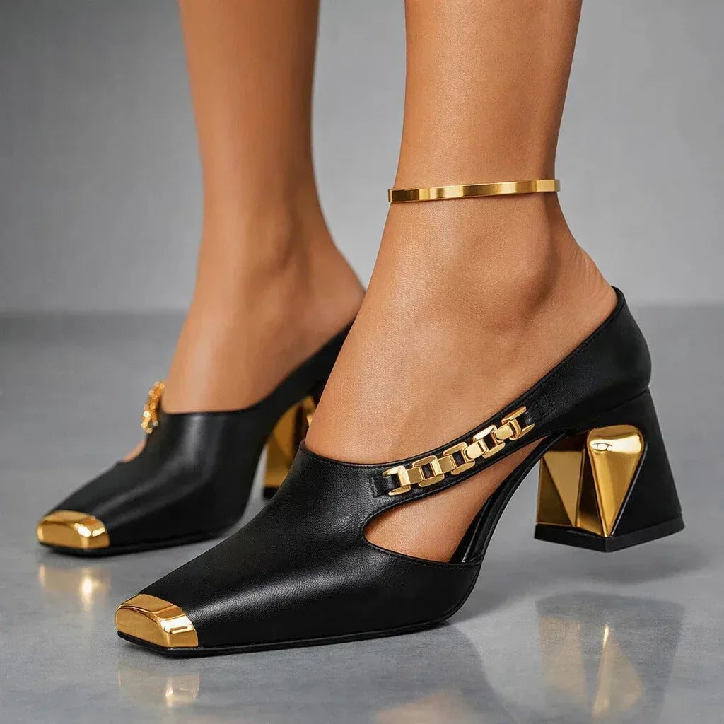 Close side profile of black mule pumps with gold sculpted heel and chain vamp trim