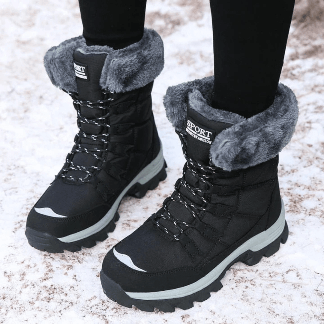 Black snow boots with grey faux fur collar, worn in snow