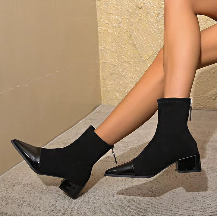 Model wearing black pointed toe ankle boots with patent panel