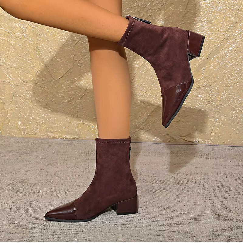Model wearing brown pointed toe ankle boots with patent panel and block heel