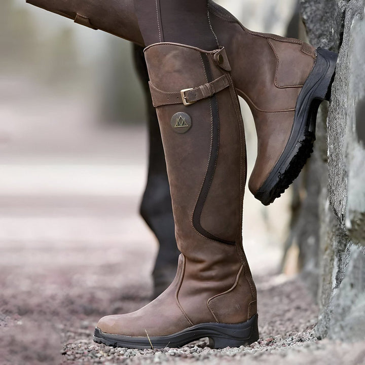 Dark brown leather knee-high riding boot with buckle strap, side view