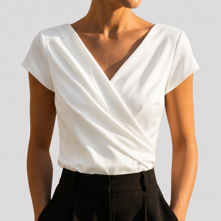 White draped wrap-front blouse with V-neckline and cap sleeves, close-up front view