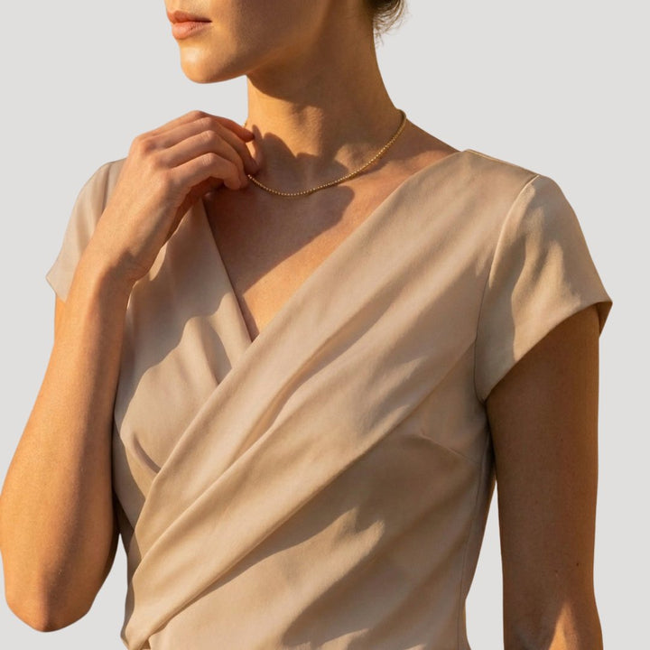 Khaki wrap-front blouse close-up showing draped neckline and cap sleeve