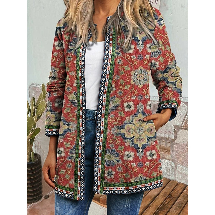Woman wearing green floral patterned open-front jacket with contrast trim over white top and jeans