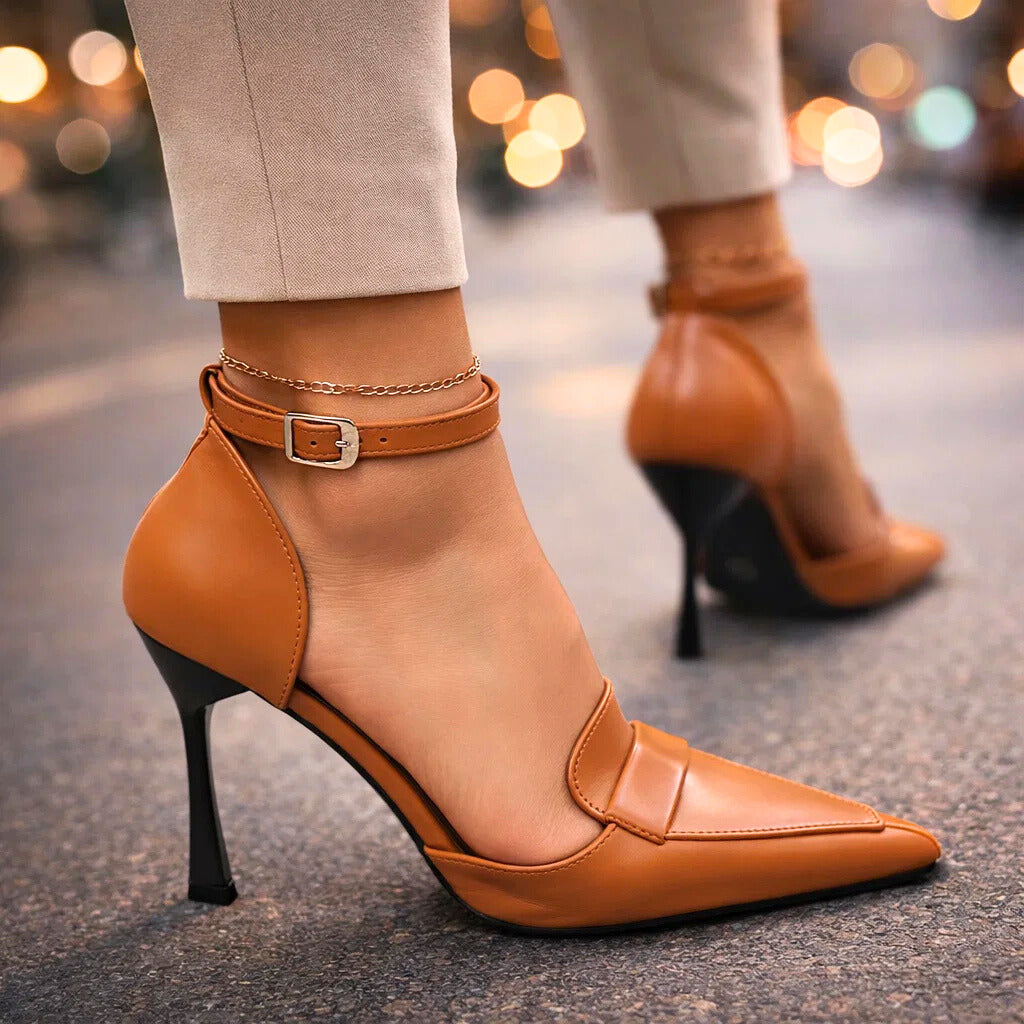 Close-up of brown pointed-toe pump with ankle strap worn walking outdoors
