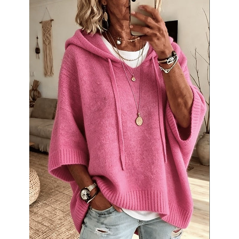 Pink hooded sweater worn with layered necklaces, front view