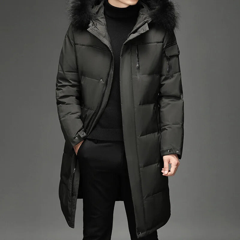 Man wearing gray hooded down coat with fur trim, front view with hands in pockets