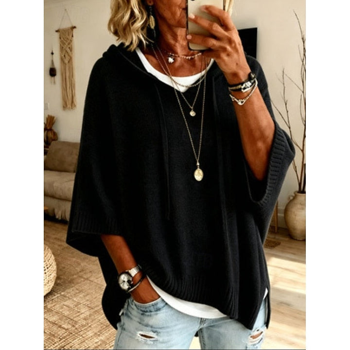 Black hooded sweater worn with layered necklaces, front view