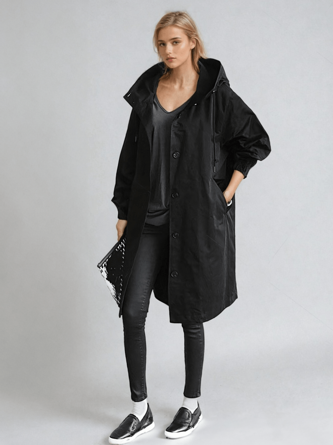 Woman wearing black oversized hooded trench coat, front view