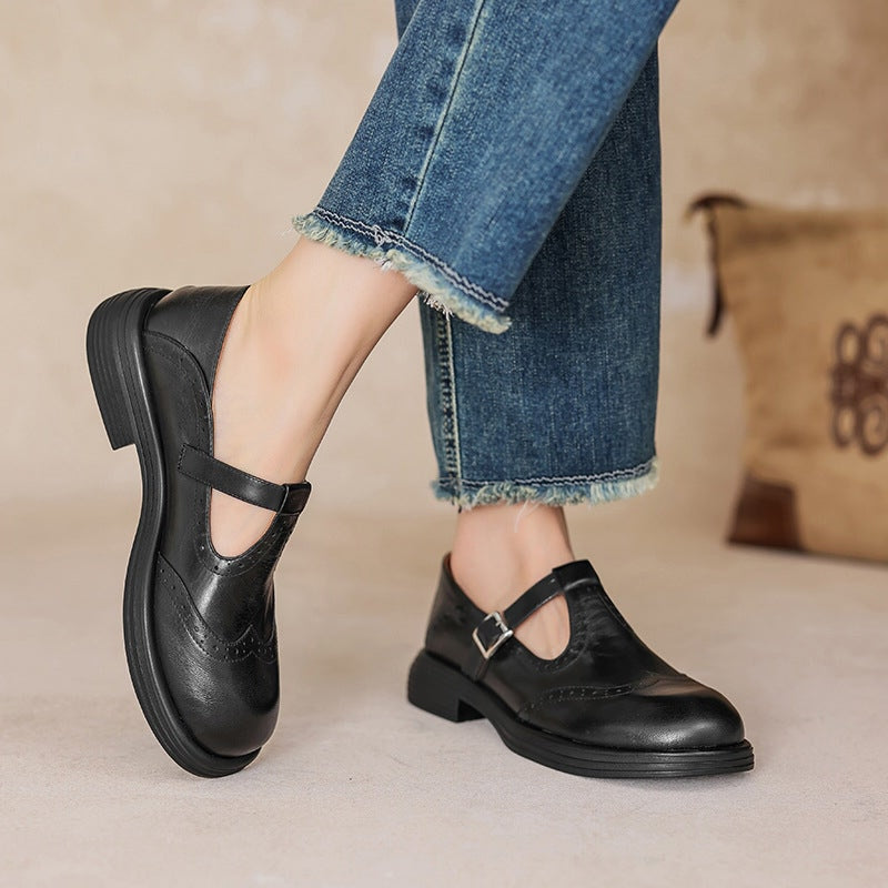 Black wingtip Mary Jane flats worn with jeans, side angle