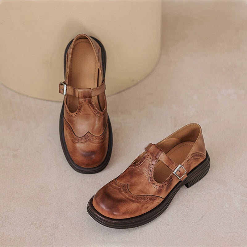 Pair of brown wingtip Mary Jane flats shown from front angle