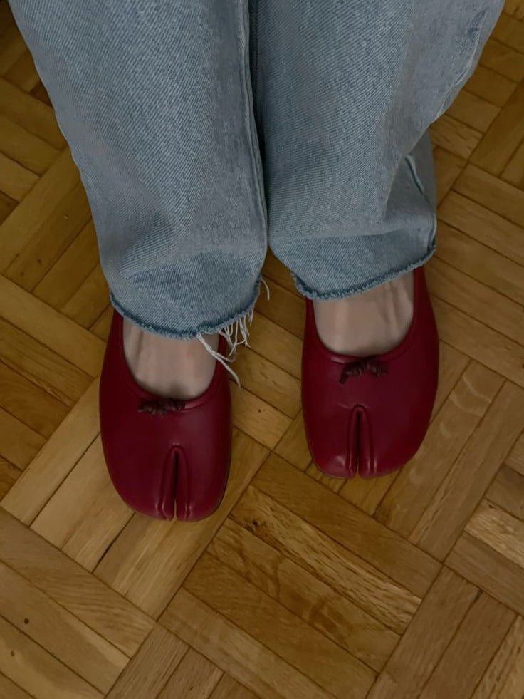 Red split toe ballet flats with cropped jeans on wood floor