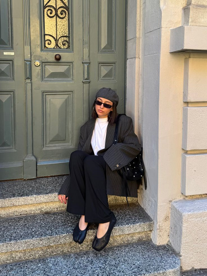 Woman in tailored outfit wearing black split toe ballet flats