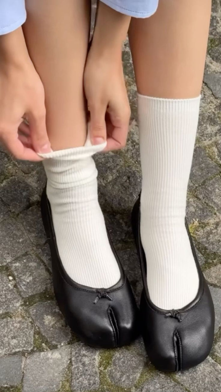 Woman wearing white ribbed socks with black split toe ballet flats