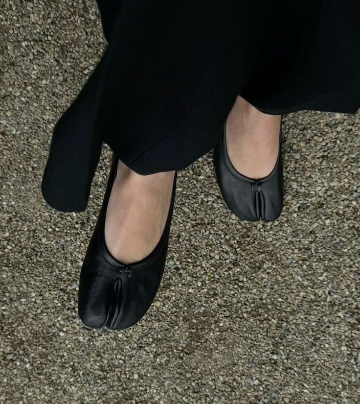Overhead view of black split toe ballet flats with flowing black skirt