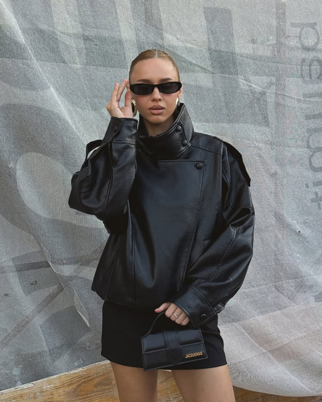 Model wearing black leather jacket with funnel collar