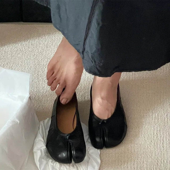 Model holding black split-toe flat showing interior