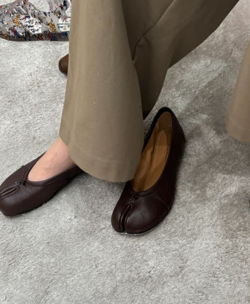 Model wearing brown split-toe flats with trousers
