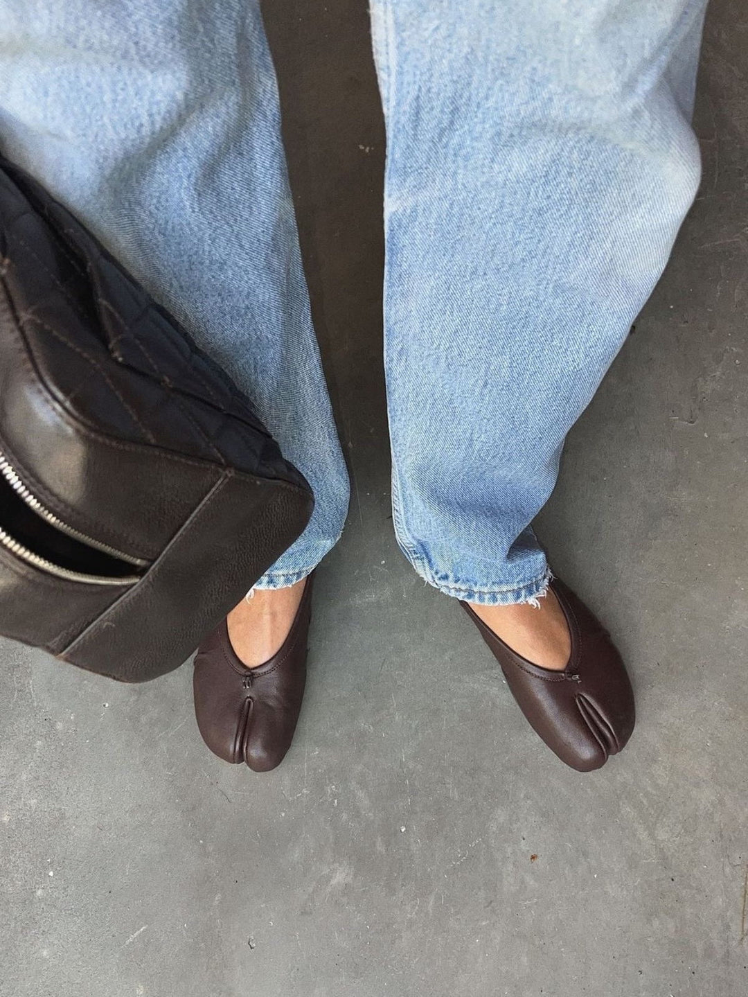Model wearing brown split-toe flats with jeans and bag