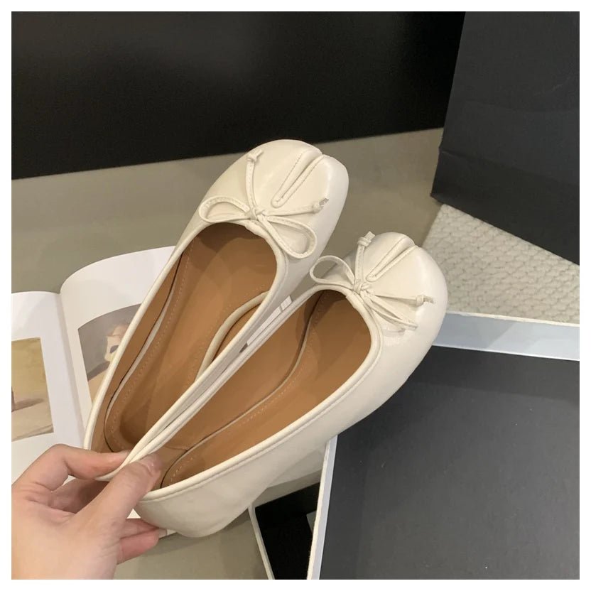 Beige tabi ballet flats held in hand