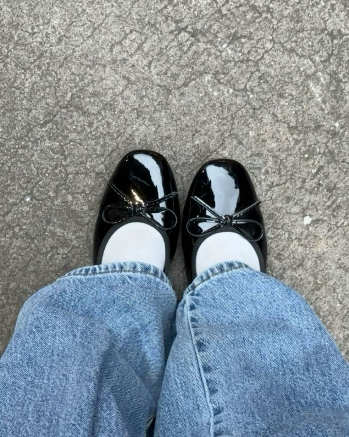 Black patent ballet flats with bow worn with jeans