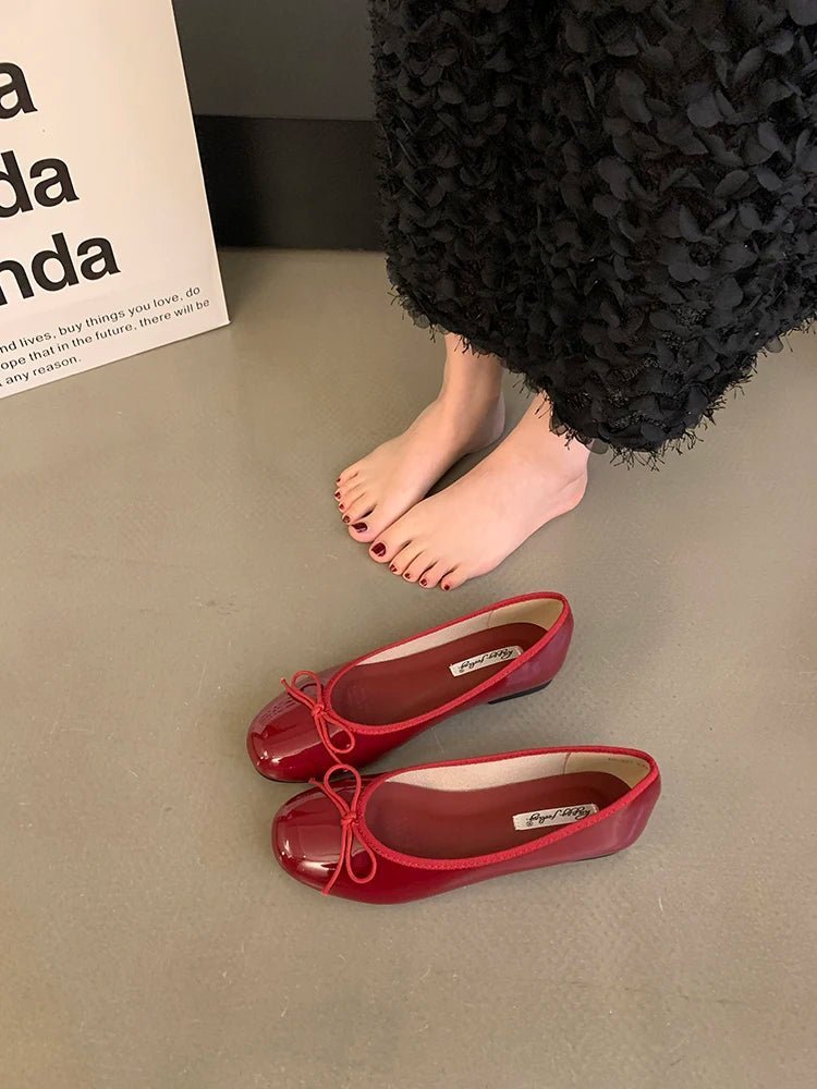 Red patent ballet flats with bow detail on floor
