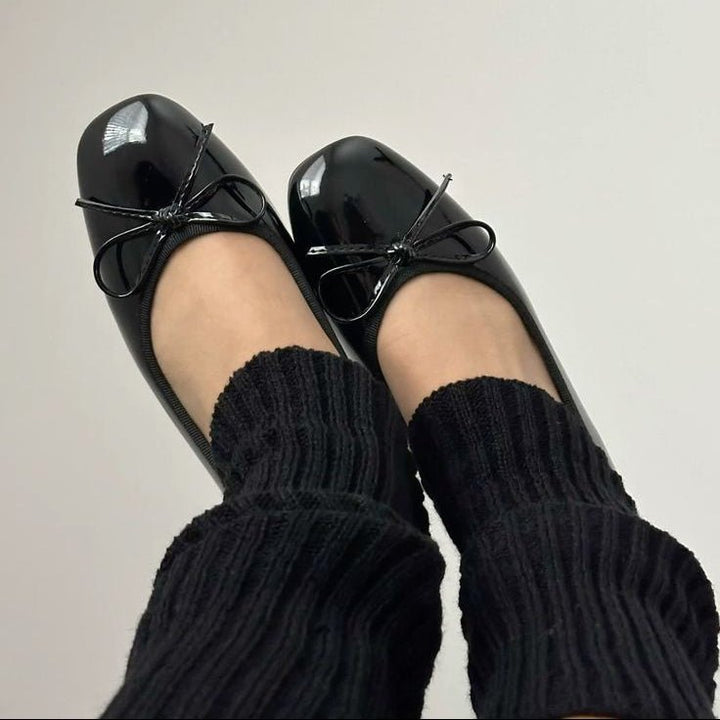 Black patent ballet flats with bow detail worn with socks