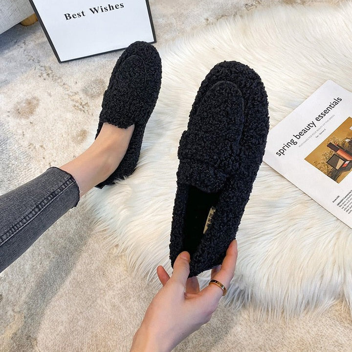 Black teddy fleece loafer slippers held in hand showing sole
