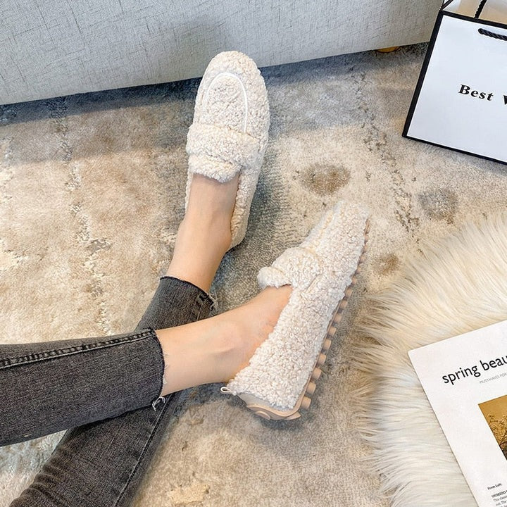 Cream teddy fleece slippers worn on feet with textured sole