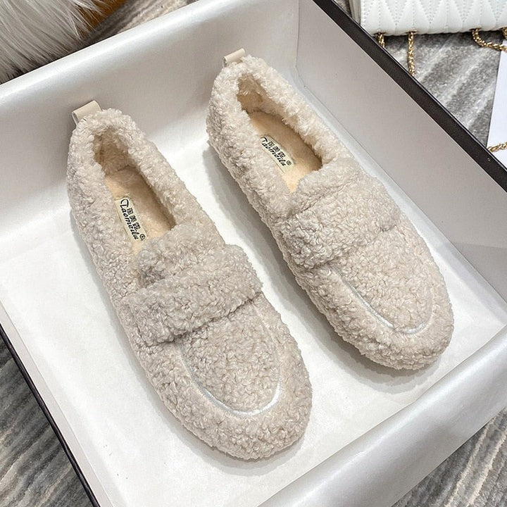 Cream teddy fleece slip-on loafer slippers on display tray