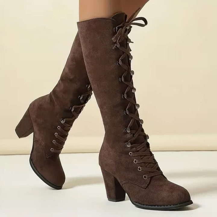 Side view of brown lace-up knee high suede boots with block heel
