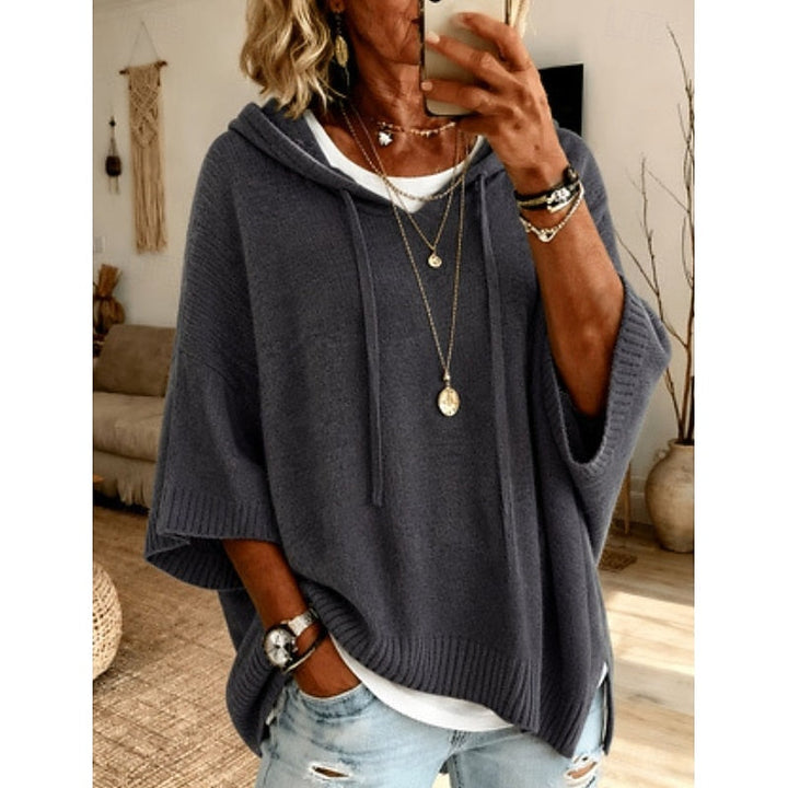 Dark gray hooded sweater worn with layered necklaces, front view