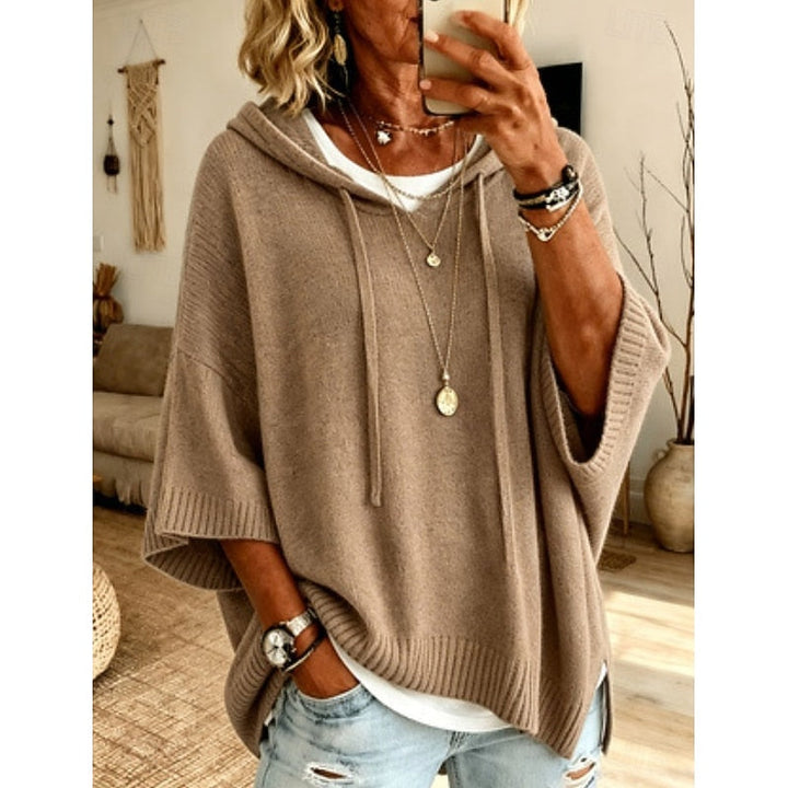 Khaki hooded sweater worn with layered necklaces, front view